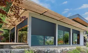 Volets roulants gris anthracite sur une maison moderne avec pergola en bois. La **couleur volet bois** des lames de la pergola contraste avec le gris des volets.
