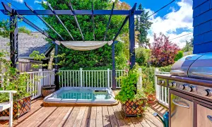 Un coin jacuzzi extérieur sous une pergola, avec un barbecue à proximité, invite à la détente.