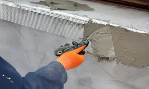 Application d'un enduit isolant extérieur avec une truelle, renforçant la façade.