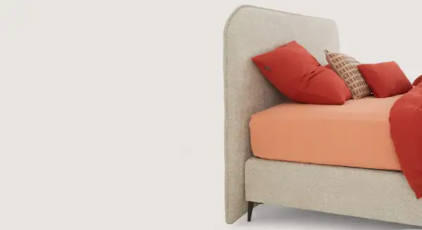 Lit moderne avec tête de lit capitonnée, drap orange vif et coussins rouges. Idées pour comment fixer tête de lit.