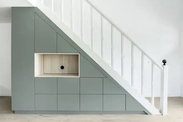 Aménagement sur mesure : un rangement sous escalier gris pâle avec des portes et une niche en bois clair.